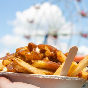 Poutine, a Canadian favorite at the fair, where junk food reigns supreme, held up in front of the ferris wheel